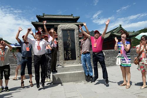 7月28日,前來參觀考察的勞動模范在北京居庸關長城“不倒長城非好漢”紀念碑前歡呼跳躍。新華社記者 何俊昌 攝